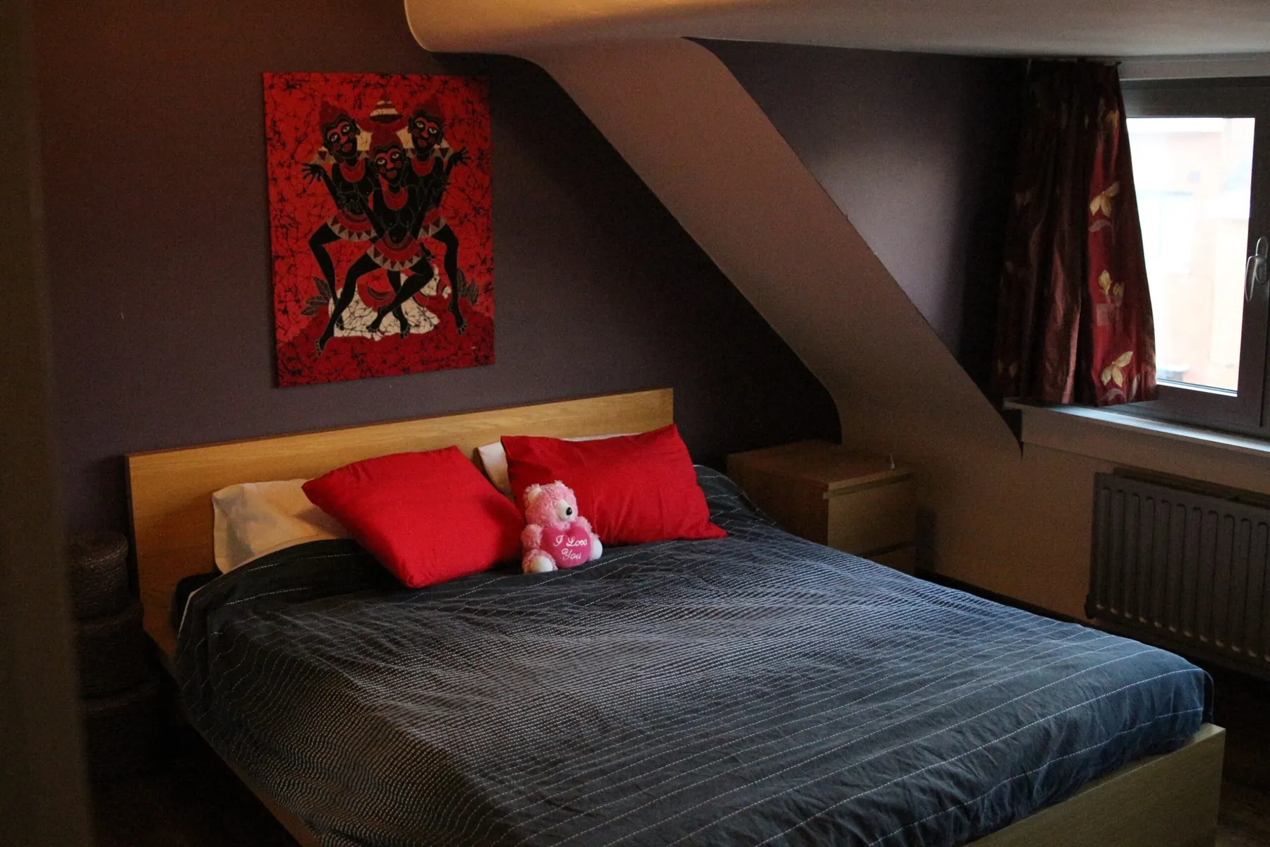 Een slaapkamer met tweepersoonsbed en eiken hoofdeinde onder het dak