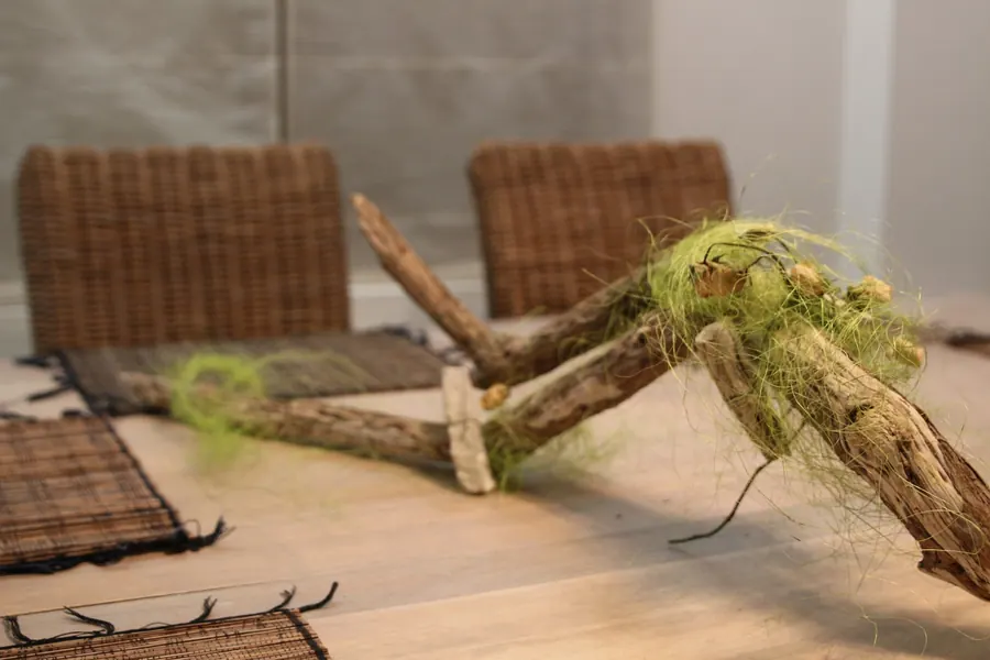 Een decoratiestuk van drijfhout en gedroogd mos op tafel